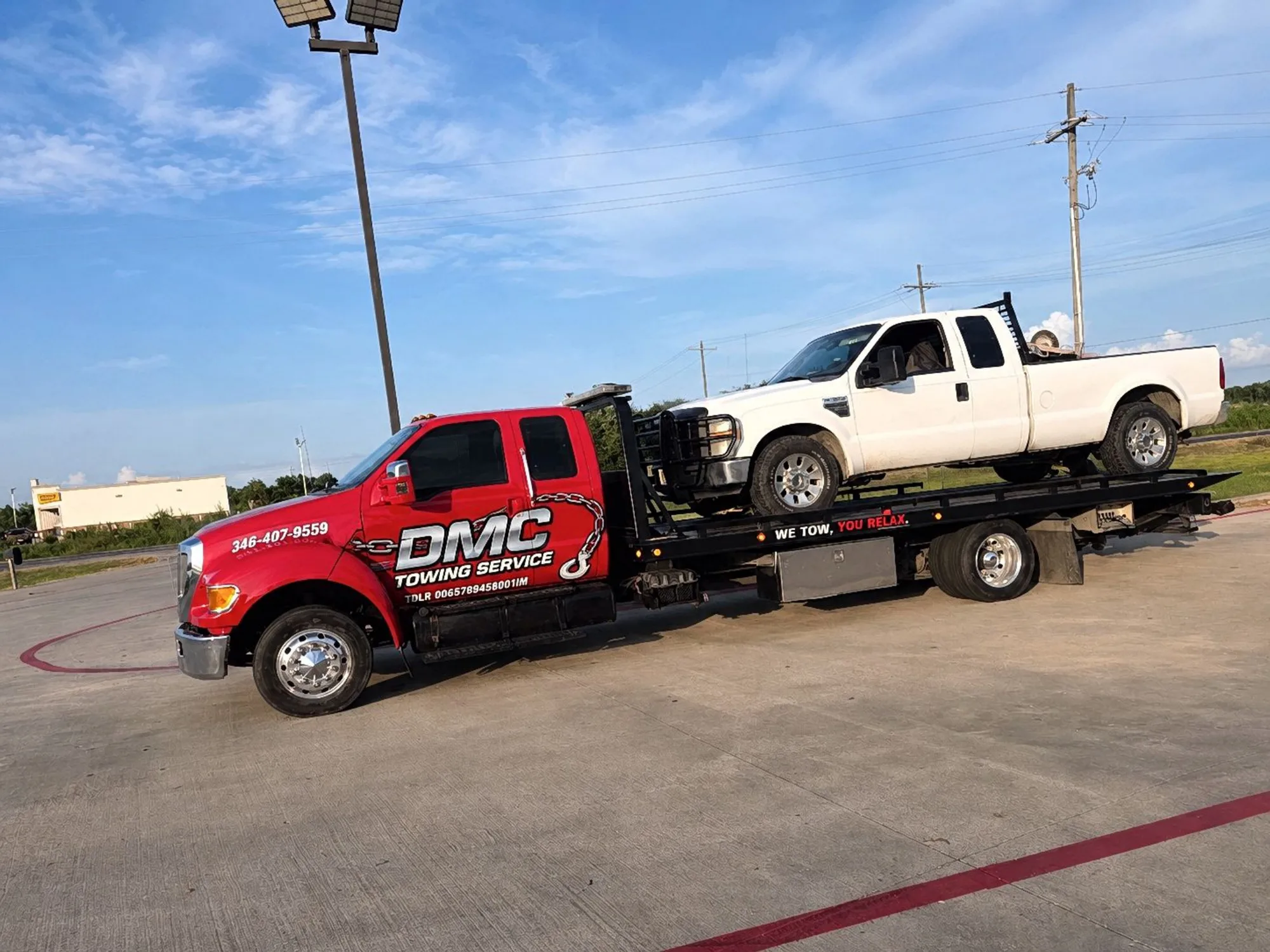 DMC Towing Service red flatbed tow truck hauling a white pickup in Spring, TX